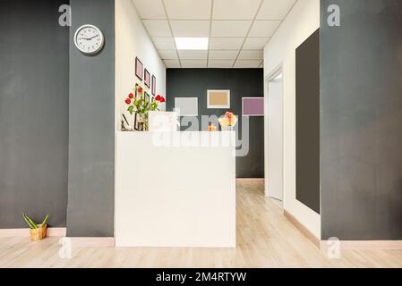 White reception desk with flowers, wooden floors and gray and white walls Stock Photo
