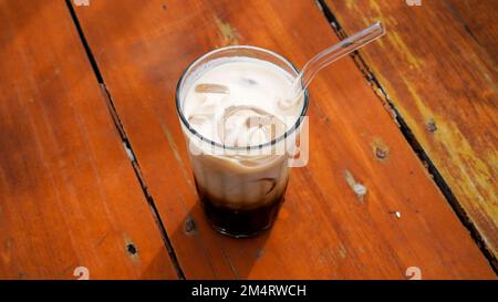 Iced cappuccino in tall clear glass served on a brown wooden table Stock Photo