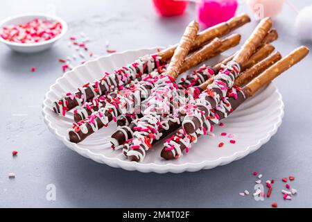 Valentines day treat, chocolate covered pretzel rods with pink and red sprinkles Stock Photo