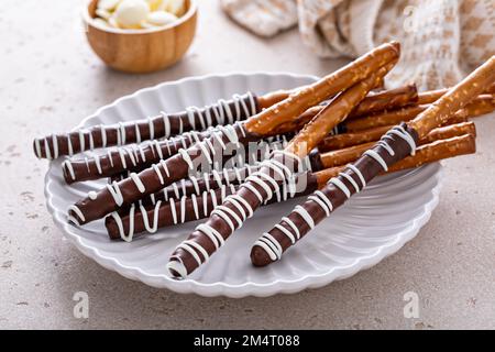Chocolate covered pretzel rods homemade on a white plate with dark and white chocolate Stock Photo