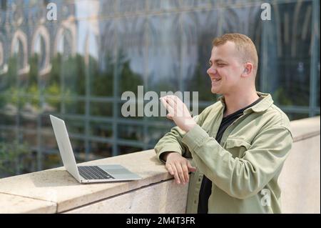 Caucasian man communicates in sign language via video link on laptop.  Stock Photo