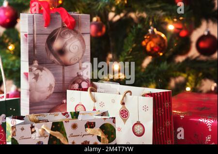 Decorated Christmas bags with gifts in front of Christmas tree Stock Photo