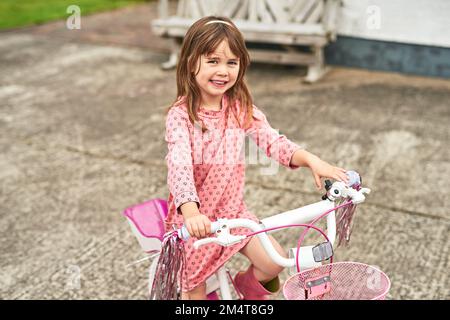 This princess gets around by bike. Portrait of an adorable little girl riding her bike outdoors. Stock Photo