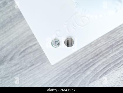 The front and back of the LR1130 coin or button cell battery sits on a table Stock Photo
