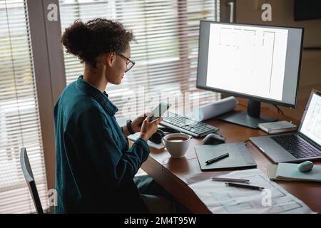 Smiling woman interior designer holding smartphone during break at home office. Freelance concept Stock Photo