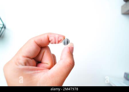 Coin cell or button cell battery LR1130 in hand, object isolated on white background Stock Photo