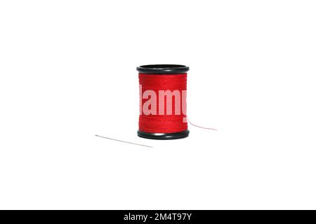 Red sewing thread in black reel with sewing needle isolated on white background. Stock Photo