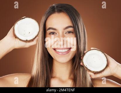 Woman, skincare and coconut in studio, happy or smile for self care, nutrition or cosmetic health. Model, skin wellness and fruit for oil, moisturizer Stock Photo