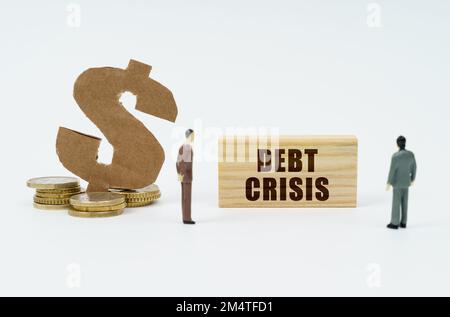 Economy and finance concept. On a white background, coins, a dollar symbol and figures of businessmen who look at a wooden plate with the inscription Stock Photo