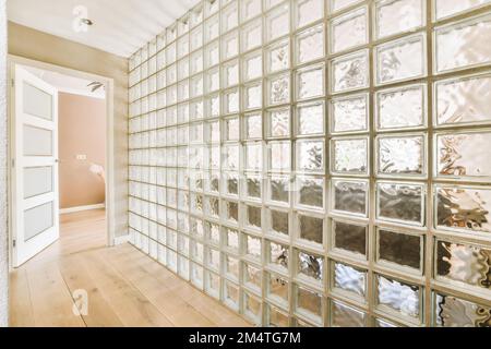 an empty room with lots of glass blocks on the wall and wood flooring in front of the window panes Stock Photo