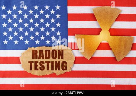 Industry and radiation concept. On the flag of the United States, there is a symbol of radioactivity and a torn cardboard with the inscription - Radon Stock Photo