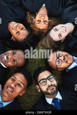 Our circle of study mates. High angle shot of a group of students relaxing on the grass together on graduation day. Stock Photo