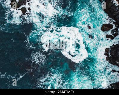 Stormy sea on a cold autumn day, top down view at the waves crushing over the rocks Stock Photo