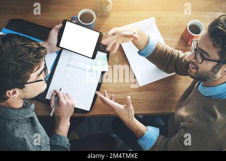 Covering every point of the project together. two businessmen working together on a digital tablet in an office. Stock Photo