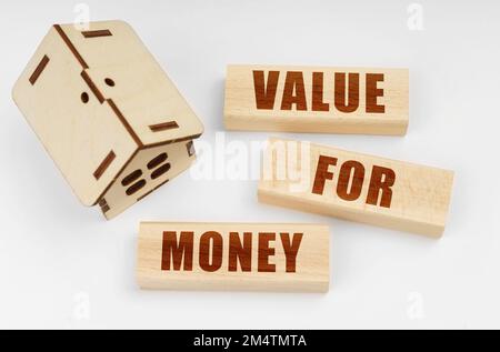 Business and real estate concept. On a white surface, a wooden toy house and blocks with the inscription - Value for Money Stock Photo