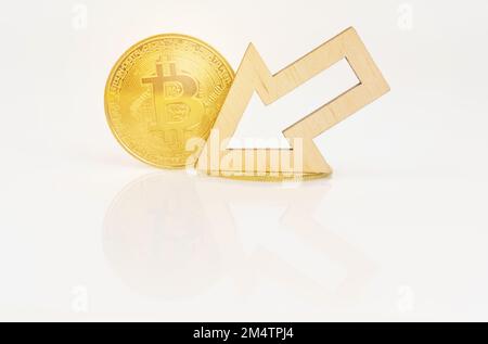 Cryptocurrency and business concept. On a white surface, bitcoin and an arrow showing a decrease in the value of the cryptocurrency. Stock Photo