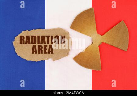 The concept of industry and radiation. On the flag of France, the symbol of radioactivity and torn cardboard with the inscription - Radiation Area Stock Photo