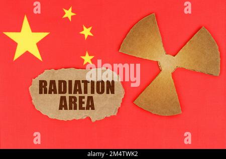 The concept of industry and radiation. On the flag of China, the symbol of radioactivity and torn cardboard with the inscription - Radiation Area Stock Photo
