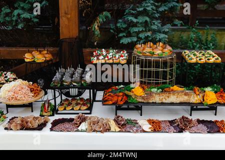 Mini burgers snacks on a wooden table, beautifully decorated catering banquet table on a corporate, christmas, birthday party event or wedding celebra Stock Photo