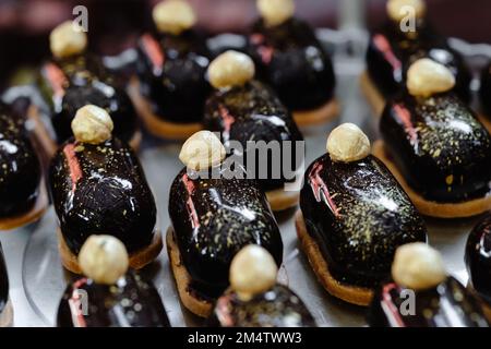 A variety of eclairs with chocolate glaze and nuts on the festive table. Stock Photo