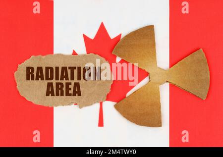 The concept of industry and radiation. On the flag of Canada, the symbol of radioactivity and torn cardboard with the inscription - Radiation Area Stock Photo