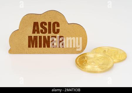 Business and technology concept. Bitcoins lie on a white surface and there is a sign - a cloud with the inscription - Asic miner Stock Photo