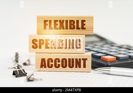 Business and finance concept. On the reports is a pen, calculator, clips and wooden boards with the inscription - FLEXIBLE SPENDING ACCOUNT Stock Photo