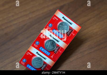 A few sealed Panasonic CR2032 3V coin batteries on wooden background. Stock Photo