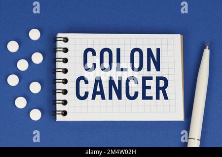 Medical concept. On a blue background, a pen, tablets and a notepad with the inscription - COLON CANCER Stock Photo