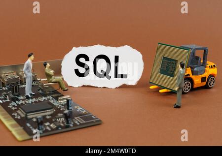 Technology and business concept. On a brown surface, a loader with a processor, a microcircuit, figures of people and torn paper with the inscription Stock Photo