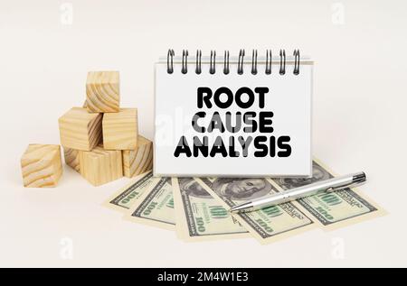 Business concept. On a white surface, cubes, dollars, a pen and a notepad with the inscription - Root Cause Analysis Stock Photo