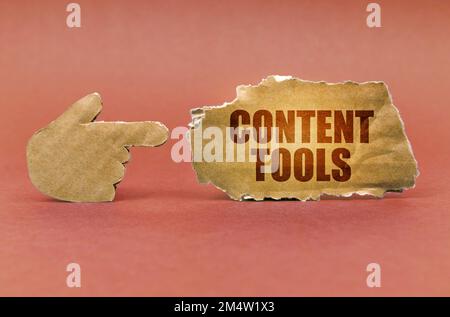 Business and technology concept. On a brown surface, a cardboard hand points to a sign that says - Content Tools Stock Photo