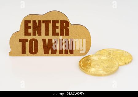 Business and technology concept. Bitcoins lie on a white surface and there is a sign - a cloud with the inscription - ENTER TO WIN Stock Photo