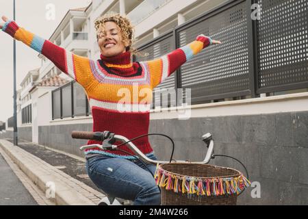 Happiness concept with overjoyed female outstretching arms riding a bike. Green transport environment lifestyle. One woman in active outdoor leisure a Stock Photo