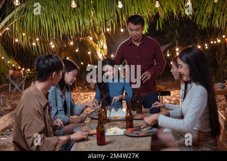 Young couple having dinner with friends at backyard party Stock Photo