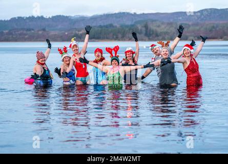 Members of the Loch Insh Dippers wild swim group take part in a Christmas-themed swim in Loch Insh in the Cairngorms National Park near Aviemore, Scotland. Picture date: Friday December 23, 2022. Stock Photo