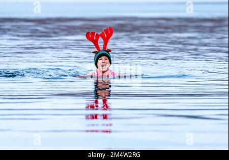 Members of the Loch Insh Dippers wild swim group take part in a Christmas-themed swim in Loch Insh in the Cairngorms National Park near Aviemore, Scotland. Picture date: Friday December 23, 2022. Stock Photo