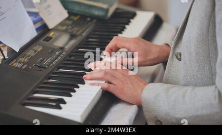 The woman plays the synthesizer. Close-up of her hands. Stock Photo