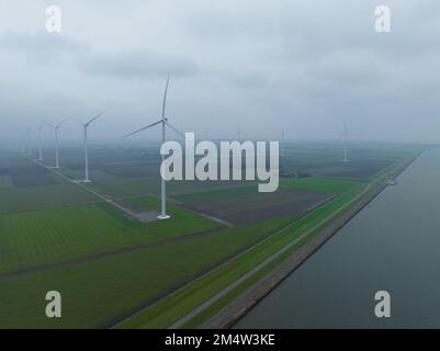Wind turbine along a dyke. WInd energy power electricity sustainable energy generation. Windmill, wind, water grass, nature. Green energy. Aerial on Stock Photo