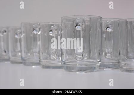 Empty transparent tea glasses stand next to each other. Focus on the ear of the cup in front Stock Photo