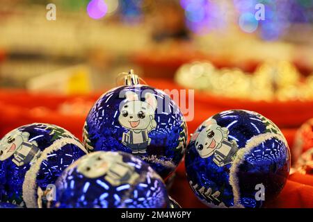 Christmas toys, blue balls with bunny - symbol of Chinese New Year 2023 on blurred festive lights background. New Year decorations in a store Stock Photo