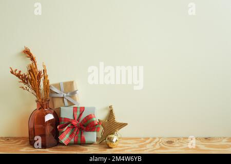 Gift boxes, vase of dry flower, christmas ornament on wooden table. ivory wall background. winter christmas, copy space Stock Photo