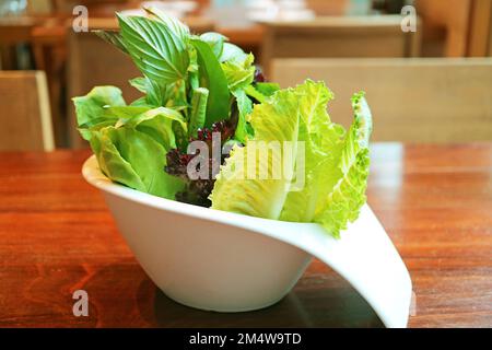 Fresh assorted vegetables in white bowl served on wooden table Stock Photo