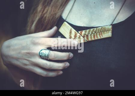 Close up woman with metal ring and wooden pendant concept photo Stock Photo