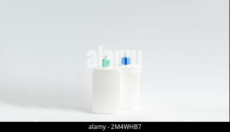 Two white unbranded bottles with a black dispenser isolated on white background. Cosmetic bottle for a cream, shampoo, oil, gel, soap, balsam. Stock Photo