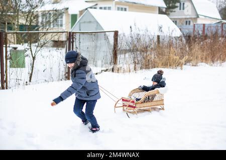 Boy pulling his friend on a sledge Stock Photo