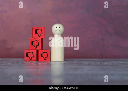 Sad wooden doll and thumbs down icon. Rejection, refusal, turn down and decline concept Stock Photo