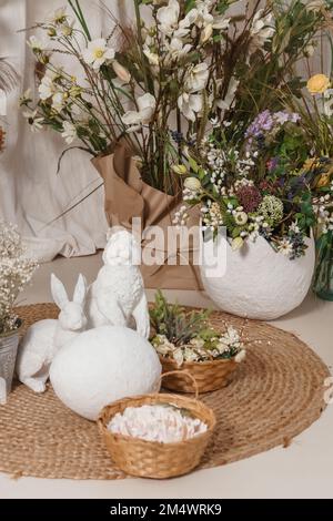 Interior floral Easter composition. Figurines of Easter bunnies and a large eggshell. The concept of home decoration for the Happy Easter holiday. Stock Photo
