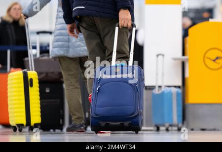 Munich, Germany. 23rd Dec, 2022. Passengers stand with their luggage at check-in counters at Munich Airport. Credit: Sven Hoppe/dpa/Alamy Live News Stock Photo