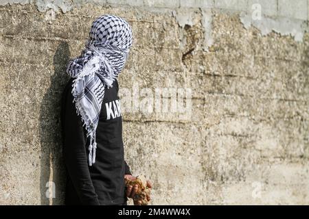 Nablus, Palestine. 23rd Dec, 2022. Masked Palestinian protester hides from the Israeli army behind a wall, during the demonstration against Israeli settlements in the village of Kafr Qaddoum near the West Bank city of Nablus. (Photo by Nasser Ishtayeh/SOPA Images/Sipa USA) Credit: Sipa USA/Alamy Live News Stock Photo